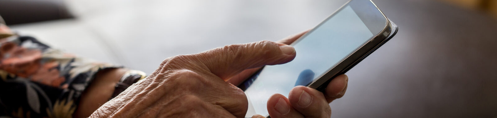 The hand of an elderly woman holding a phone.